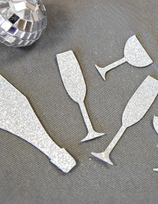 Gros plan sur la texture pailletée des confettis de table champagne argentés coupes et flûtes