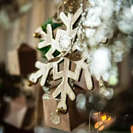 Gros plan sur le grelot et les paillettes des flocons en bois de Noël pour décoration avec paillettes et grelots or