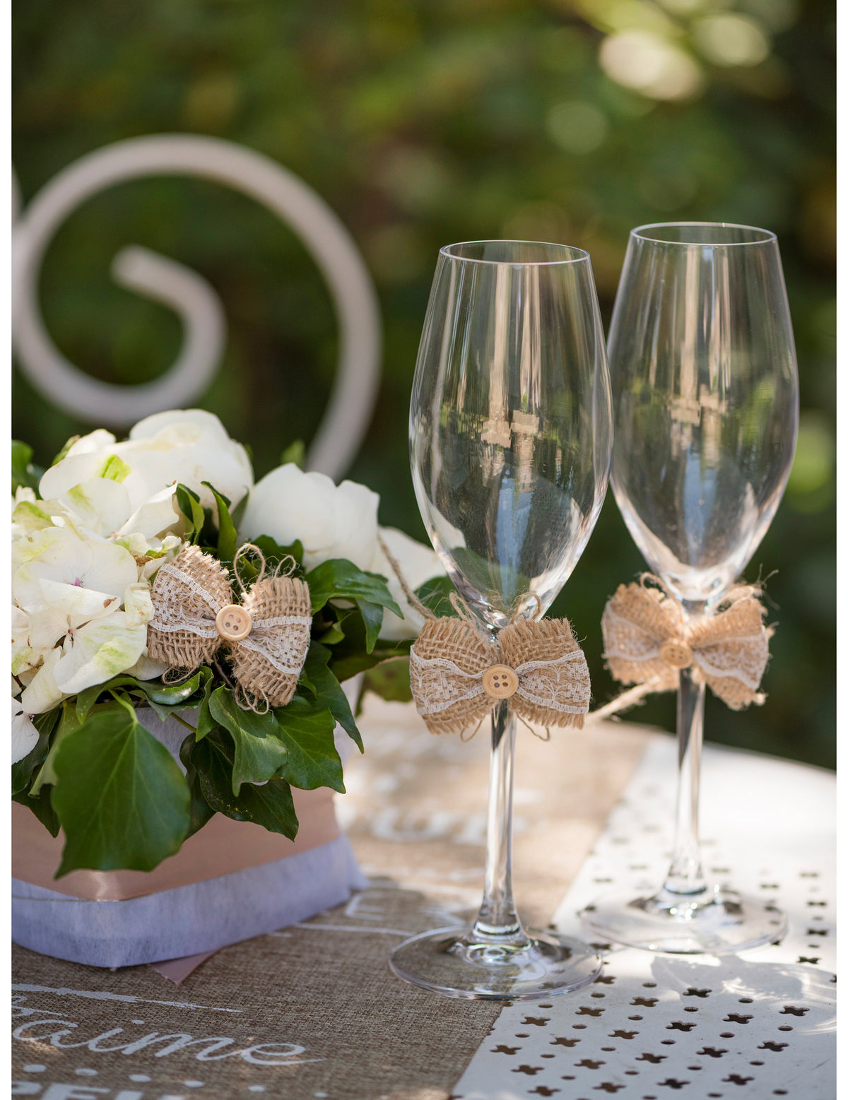 Mise en situation sur flûtes à champagne du mini nœud champêtre pour décoration en jute et dentelle avec bouton en bois