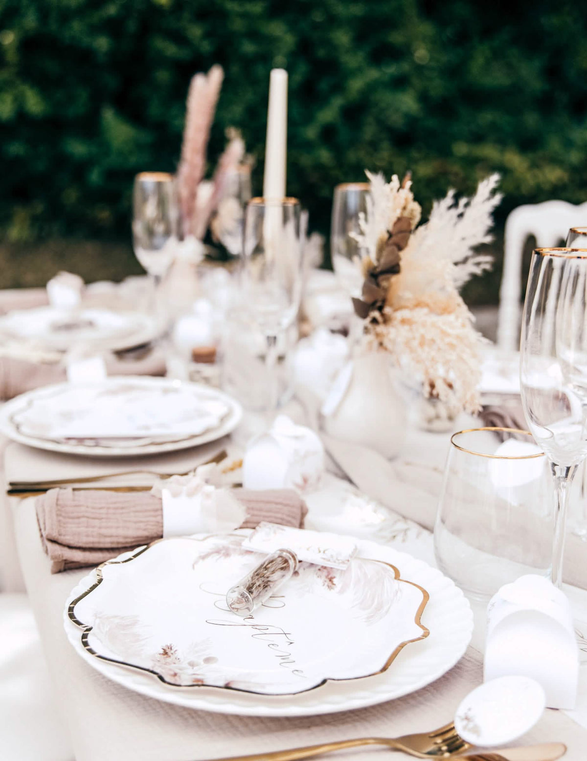 Gros plan sur le dressage de table des assiettes baptême pampas et fleurs de coton