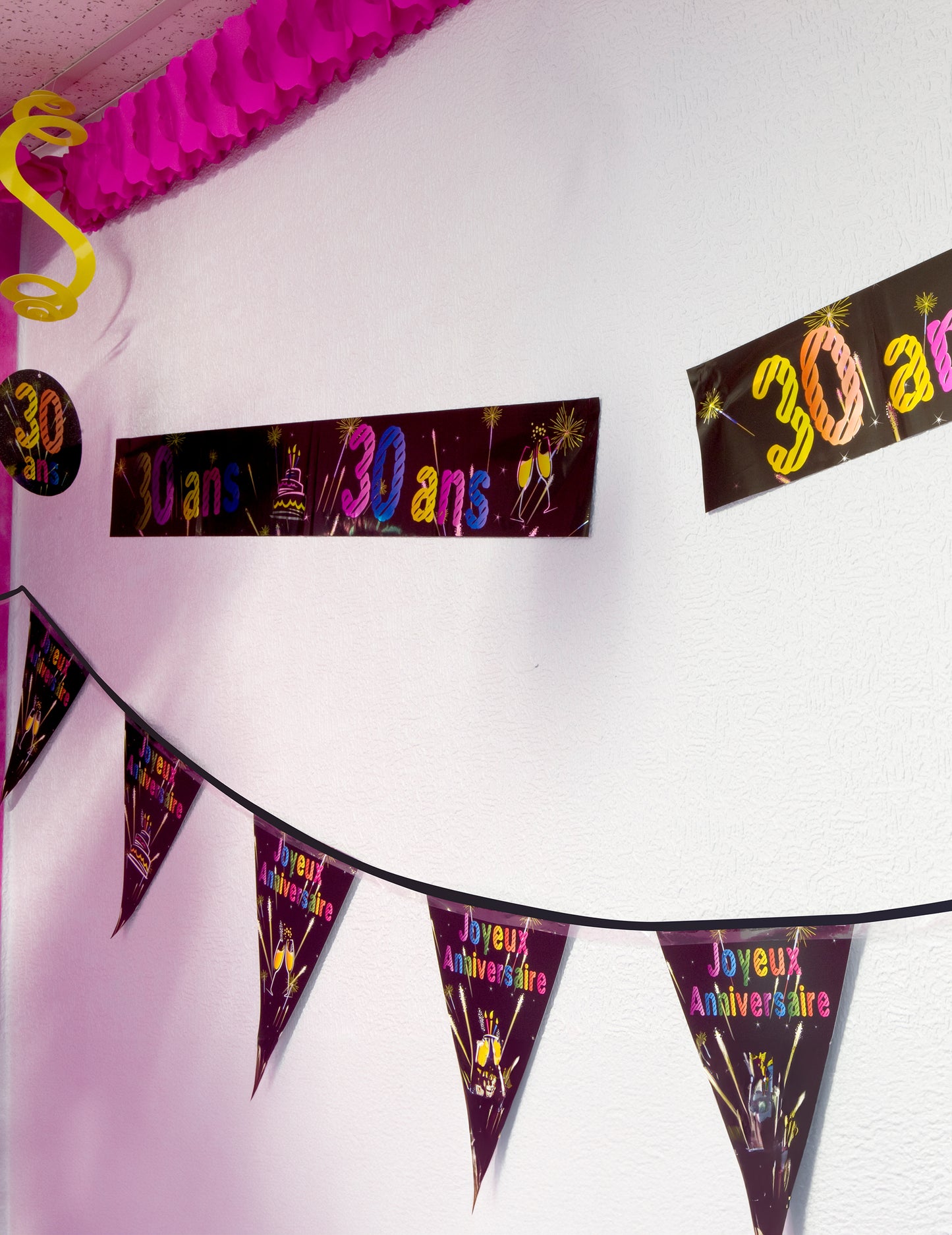 Mise en situation sur un mur de la bannière métallisée Joyeux anniversaire