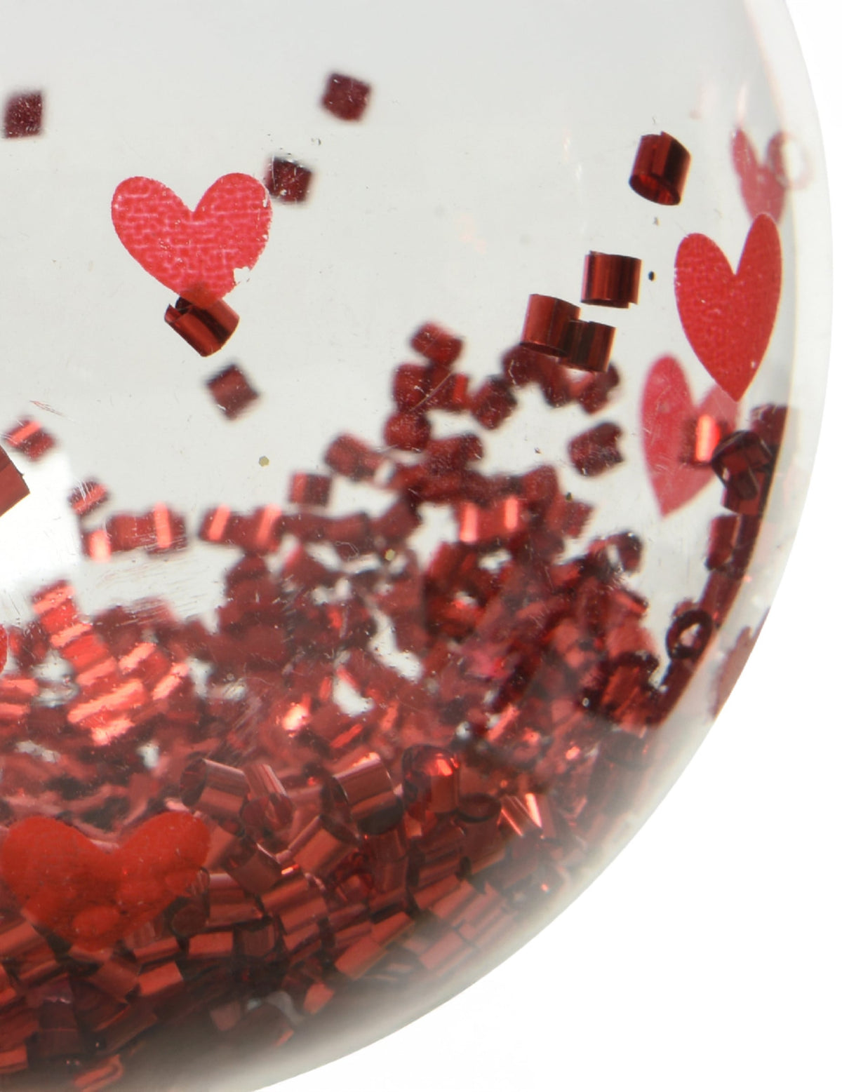 Gros plan sur les confettis et motifs de la boule de noël avec cœurs rouges et confettis brillants