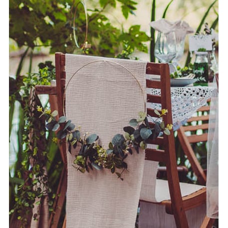 Mise en situation sur un dossier de chaise de la couronne en métal d'eucalyptus et fleurs blanches cercle or