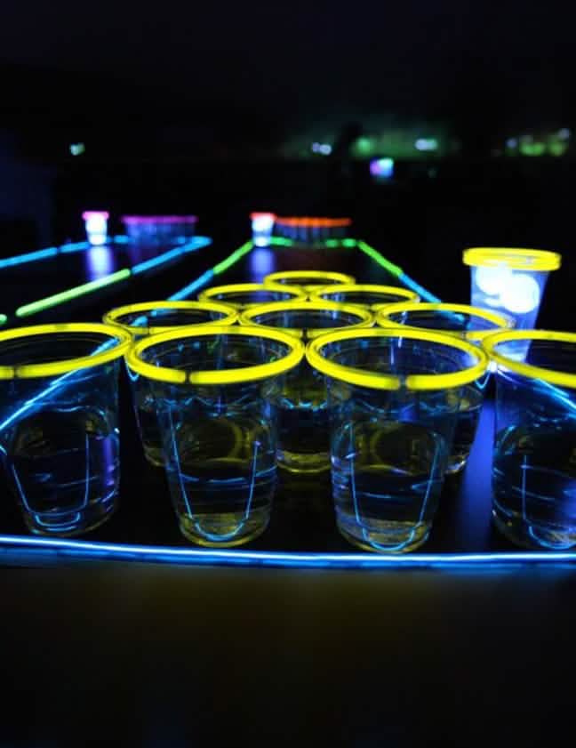 Bližnji posnetek rumenih kozarcev iz svetlečega kompleta beer pong za zabavo