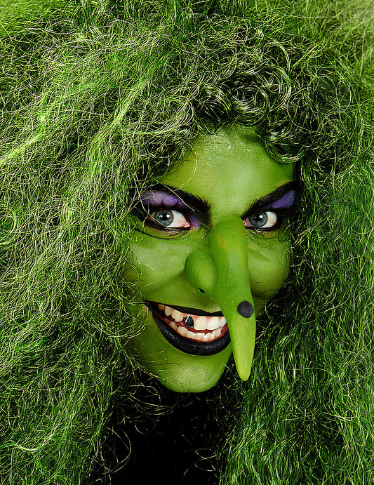 Gros plan sur le visage maquillé en sorcière du maquillage professionnel à l'eau pour visage et corps vert