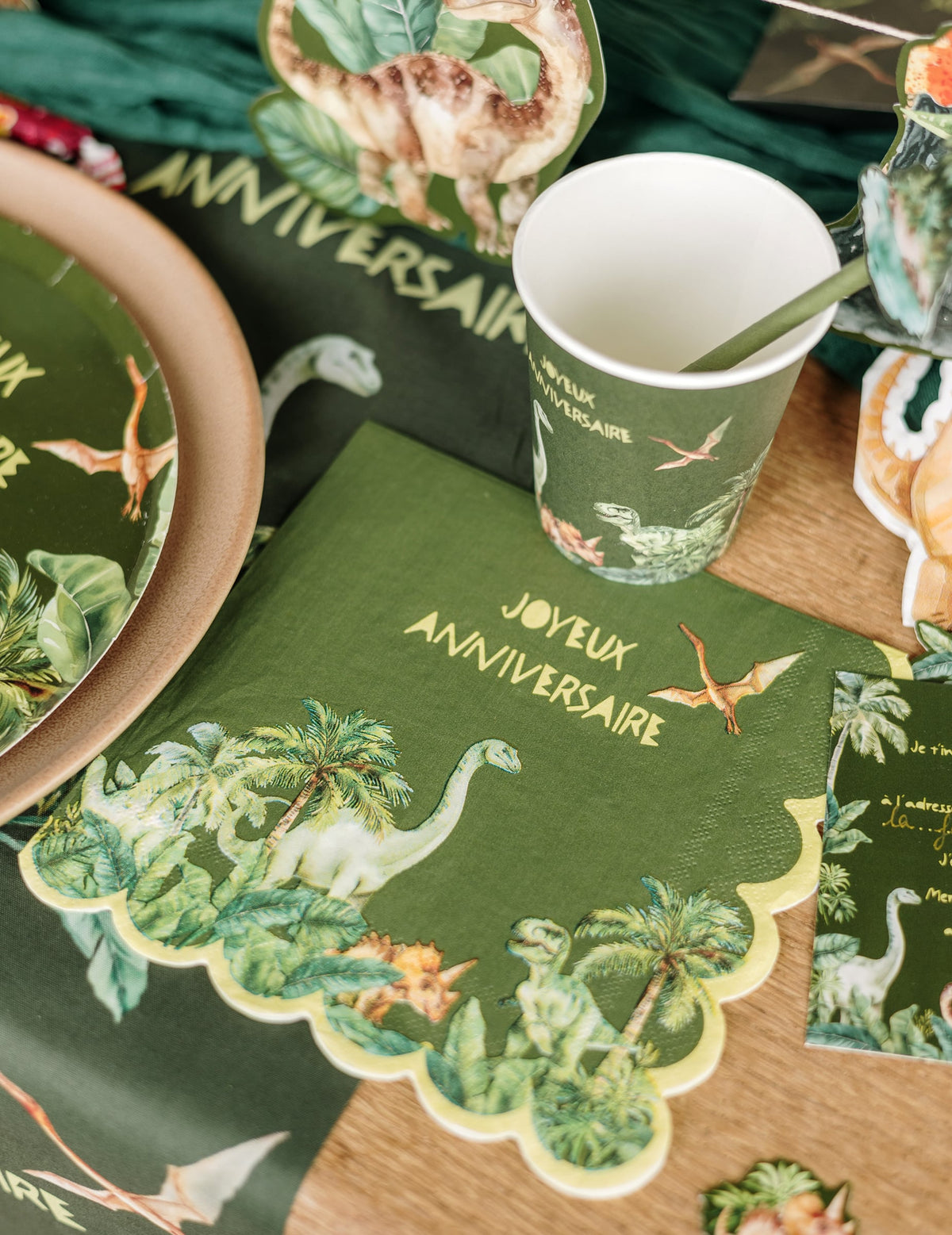 Mise en situation sur une table des serviettes en papier festonné joyeux anniversaire dinosaures