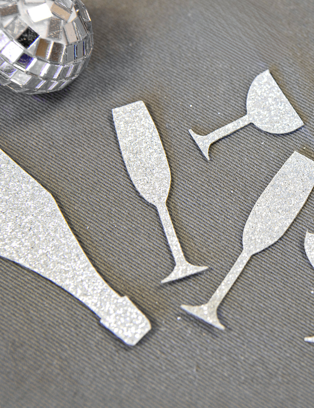 Gros plan sur la texture pailletée des confettis de table champagne argentés coupes et flûtes