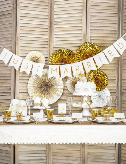 Mise en scène sur table de fête des rosaces décoratives en papier blanches et dorées