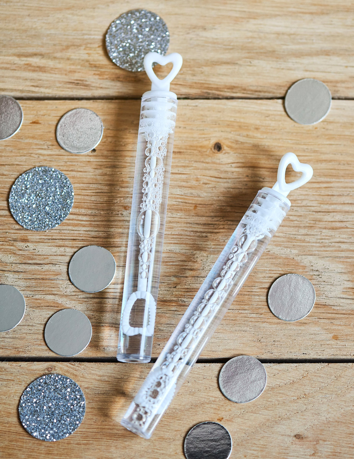 Détail avec confettis des flacons à bulles en forme de coeur pour mariage blanc