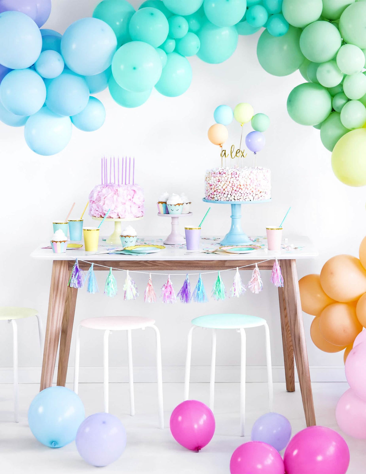 Postavitev z lokom iz balonov in pastelnimi oblogami za cupcake samorogi
