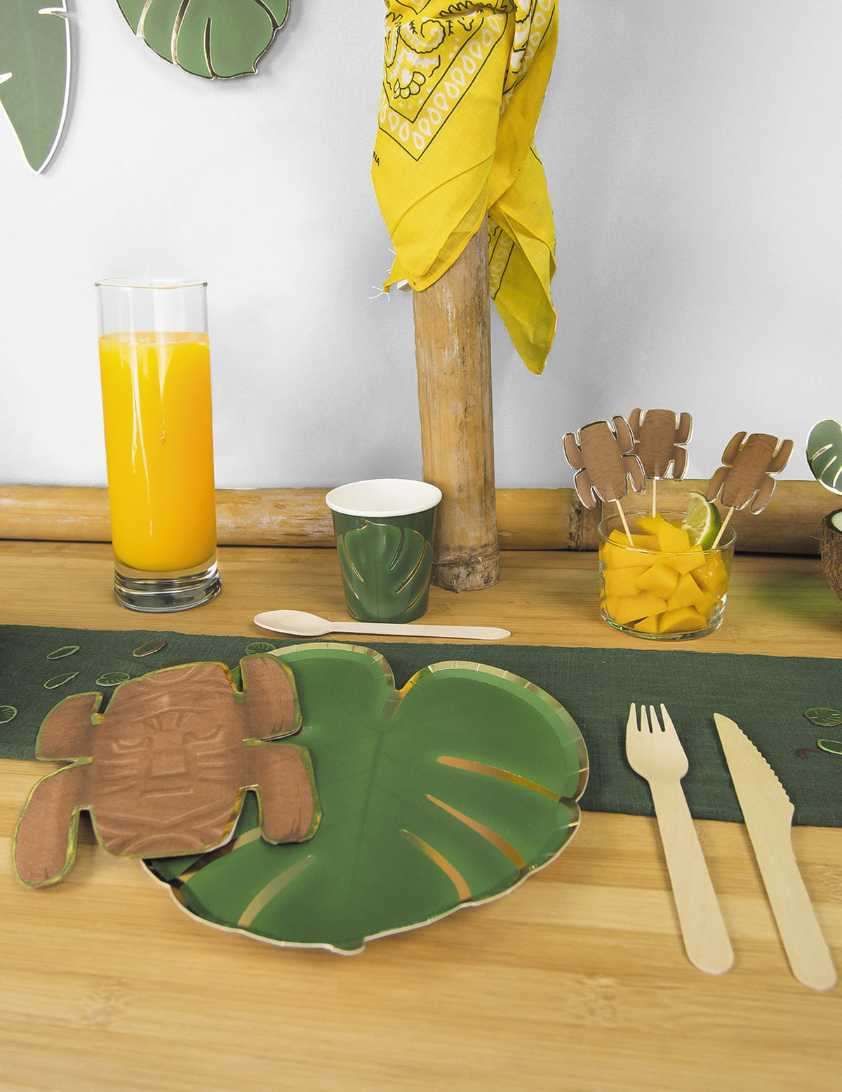 Mise en situation sur une table de fête des assiettes en carton feuilles tropicales