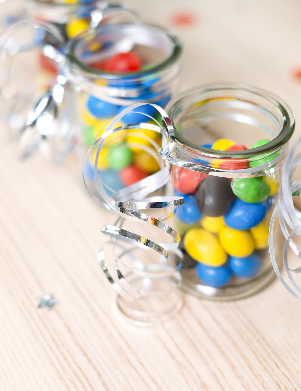 Mise en situation sur des petits pots de bonbons du bolduc brillant pour décoration de fête argent