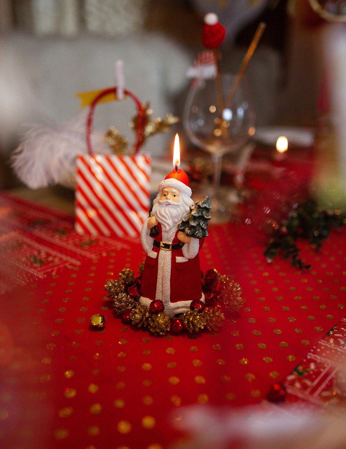 Mise en situation sur une table de fête de la bougie Père Noël avec sapin et hotte