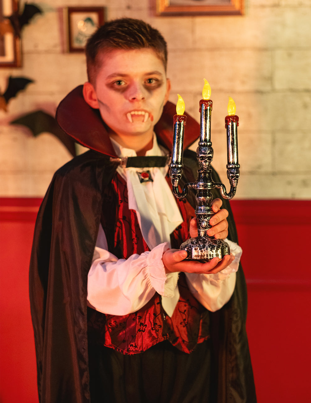 Mise en situation tenue par un enfant du chandelier à 3 branches LED têtes de mort pour Halloween