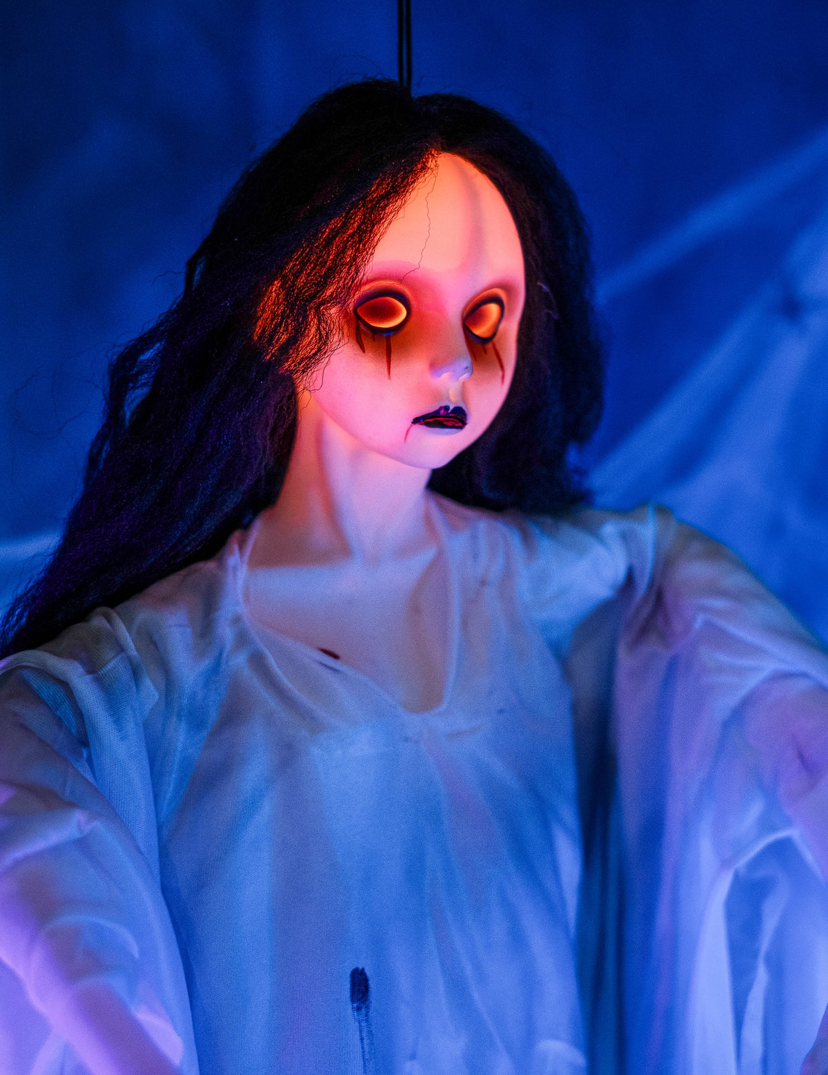 Gros plan sur le visage aux yeux lumineux de la décoration à suspendre dame blanche pour Halloween