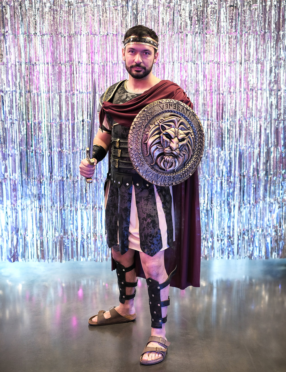 Mise en situation sur fond argenté brillant du déguisement de gladiateur romain pour homme