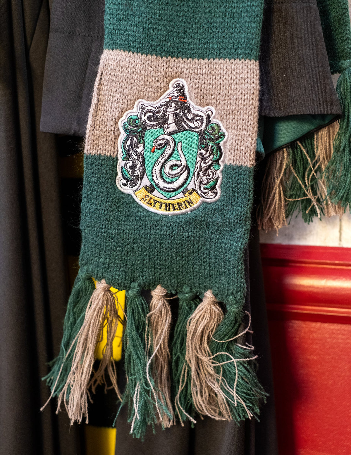 Zoom sur l'écusson et les pompons de l'écharpe luxe Serpentard