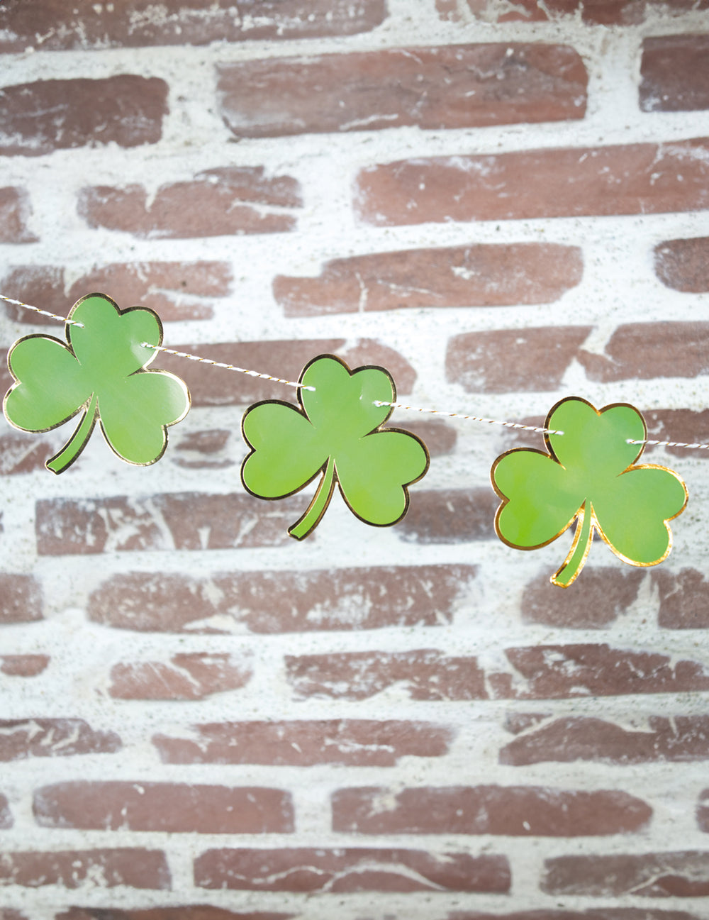 Vue en situation sur un mur de briques de la guirlande trèfles Saint Patrick