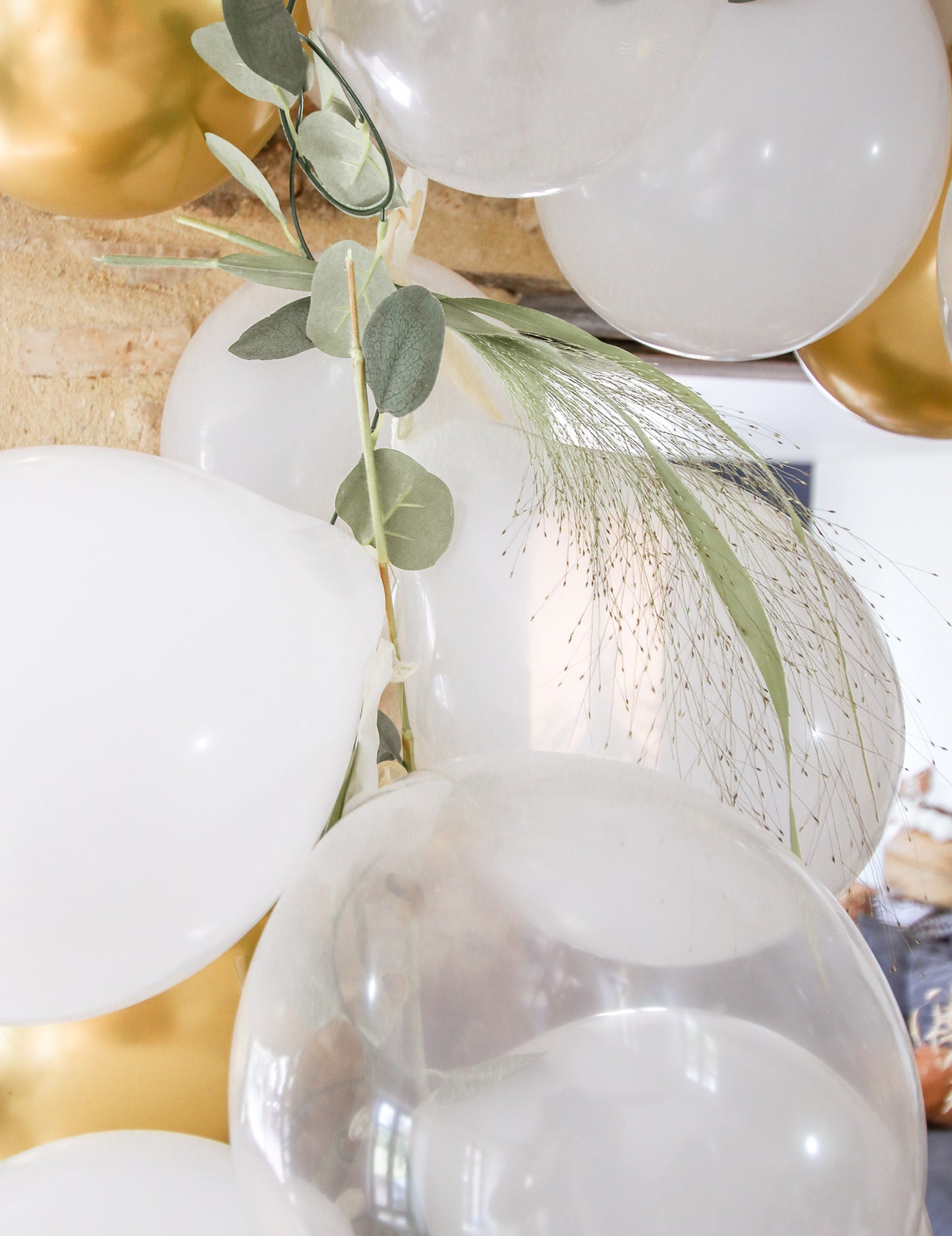 Komplet 60 balonov v obliki loka v beli in zlati barvi z listi evkaliptusa