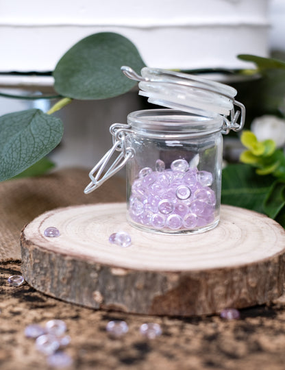 Gros plan sur le bocal sur rondin de bois des perles effet goutte de pluie pour décoration de table parme