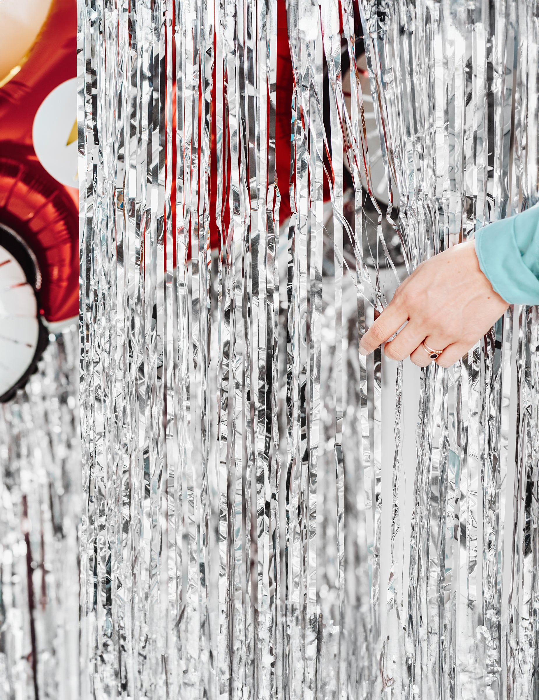 Roka, ki odmiče rese svetleče zavesa za zabavo v srebrni barvi