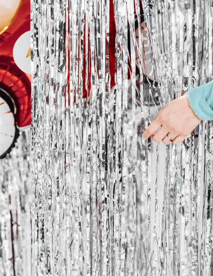 Roka, ki odmiče rese svetleče zavesa za zabavo v srebrni barvi